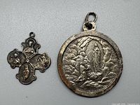 Photo of two vintage sterling silver Catholic medals: round pendant and cross medal, showing front details.