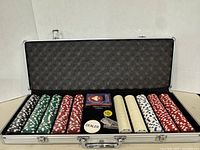 Open aluminum case showing organized poker chips, playing cards, dealer button, and small accessories inside.