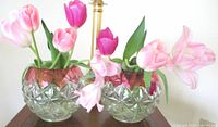 Pair of heavy pressed glass cranberry flash rose bowl vases with floral pattern and rayed base, filled with tulips.