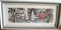 Framed vintage lithograph print shown front view, depicting a vintage village street with houses and trees.