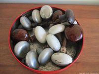 Round ceramic and metal door knobs displayed in a round container; colors include white, brown, and silver.