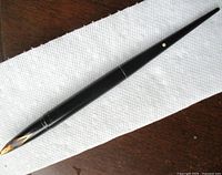 Full view of the black Sheaffer antique desk fountain pen showing the tapered slender body with gold accent dot and gold nib end.
