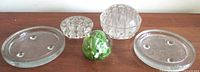 Photo showing all five items including the lime green and white art glass paperweight, two clear glass frog flower holders, and two round mottled glass footed coasters