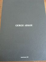 Black folder with "Giorgio Armani Spring Summer 1998" printed in white text on the cover.