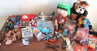Full view of the vintage toy lot showing plush toys, collectible action figures, horses, planes, and card games.