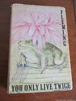 Front dust jacket of the book showing frog, dragonfly, pink flower, and title with author 'Fleming'