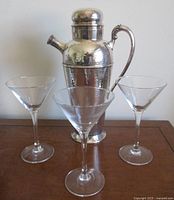 Front view of hammered Birks cocktail shaker with three clear martini glasses arranged around it.