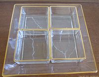 Top-down view capturing the large square glass tray with gold trim and four smaller square dishes placed inside it.