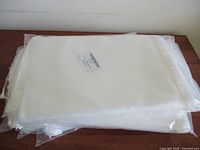 Stack of nine clear resealable polyethylene bags in original packaging, flat and translucent white.