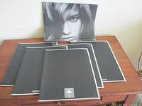 Five black-and-white Giorgio Armani 02/03 look books arranged on a wooden surface, cover view showing minimalist design