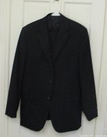 Black men's suit jacket hanging on white plastic hanger on a door, showing front with two buttons.