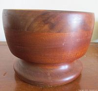 Side view of mid-century modern teak pedestal bowl showing the rounded shape and wood grain.