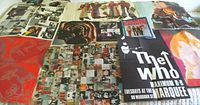 Multiple music posters and prints spread out, including The Who event poster and a collage of photos and images related to music.