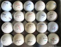 Top view of 22 vintage used golf balls showing various brands, numbers, and wear.