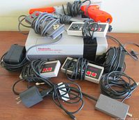 Vintage Nintendo Entertainment System console with multiple gaming controllers and accessories laid on a surface.