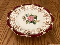 Top view of porcelain pedestal cake plate showing floral center and burgundy gilt border