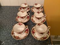 Six cups and saucers arranged on countertop showing pattern and quantity