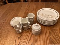 Stack of dinner plates, six cups with saucers and lidded sugar bowl