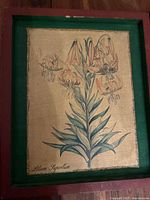 Front view of antique framed botanical illustration showing Lilium Superbum with multiple flowers and leaves on beige fabric.