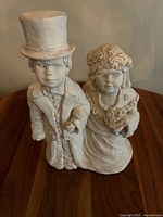 Front and side views of the ceramic wedding couple sculpture depicting bride and groom in detailed attire and facial features.