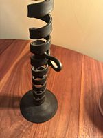 Full view of antique wrought iron candle holder showing spiral lift mechanism and base