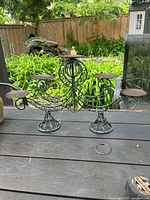 Full front view of bronze-colored metal candleholder with ornate wrought iron design showing three candle platforms and circular base stands.