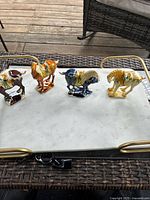 Top view showing all four ceramic horse figurines in different colors on a white marble tray