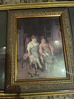 Close-up photo of the framed reproduction print showing two children seated and putting on shoes in a dimly lit room.