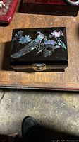 Top view showing black lacquer jewelry box lid with abalone shell bird and floral design