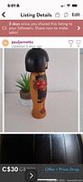 Front view of kokeshi doll showing floral body design and bob-cut black hair