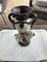 Front view of the ivory vase with brown handles and decorative details on a marble table.