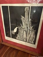 Framed linocut print of stylized winter lilies with black and white design and red mat