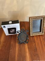 Overview of three frames including unopened 5x7 frame, black oval ornate frame, and gold-toned ornate rectangular frame