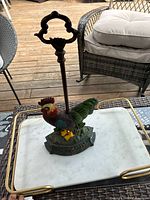 Front view of the cast iron cockerel door stop on a tray, showing its full height and base.