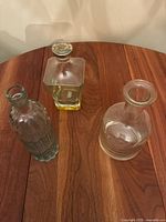 Top view of three distinct clear glass decanters showing their different shapes and stoppers on a wooden surface.