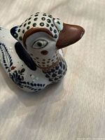 Close-up photo of the ceramic blue bird figurine showing detailed hand-painted patterns and the bird's face