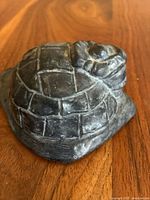 Close-up photo of soapstone wolf resting on an igloo sculpture showing carved details and stone texture.