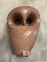 Front view of vintage beige pottery owl sculpture showing large round eyes and smooth rounded body with subtle black speckles.