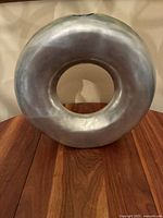 Four-sided view of vintage brutalist sculpture showing rounded hollow form with metallic finish placed on wooden table, emphasizing shape and condition.