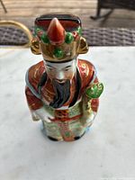 Top-down and angle front view of the vintage Chinese Fu Xing porcelain figurine, showing detailed multicolor design and face.
