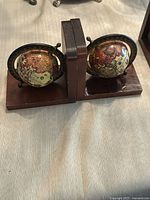 Pair of vintage wooden globe bookends showing side-by-side facing outward with globes and wood bases visible.