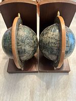 Front view of the pair of vintage old world globe bookends showing the globes and wooden bases
