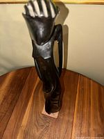 Side angled view showing the head, upper torso, and hand of the blackstone sculpture with polished finish and carved details of an abstract figure.