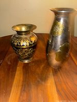 Side view showing both vases on a wooden surface, highlighting the decorative patterns and shape.