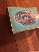 Rectangular storage box with turquoise lid decorated with a bird, nest and eggs design.