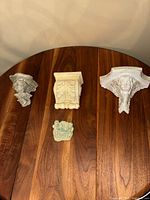 Four vintage French wall sconces arranged on a wooden surface showing varying sizes and designs.