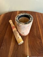 Wooden mortar and pestle set displayed on wooden surface, showing distressed and used condition