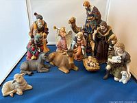Front view of entire nativity set showing all 10 porcelain pieces arranged on blue cloth backdrop