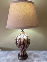 Full view of ceramic Art Deco table lamp with beige and brown marbled glaze, metal base, and beige fabric lampshade.