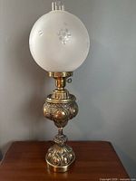 Full view of antique brass Victorian gone with the wind lamp with frosted glass globe showing overall height and base detail